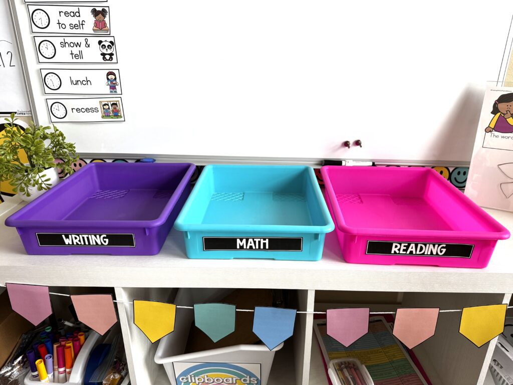 color coded turn in trays.  Purple that has a label that says writing.  blue with a label that says math.  And Pink with a label that says reading.