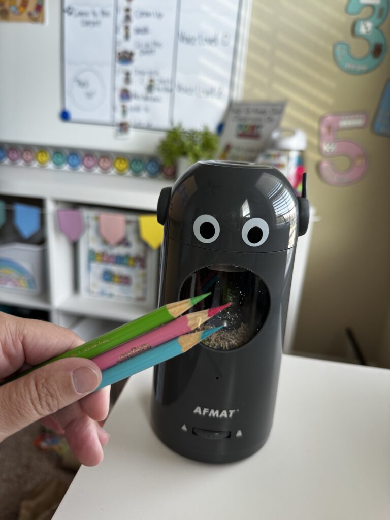 an electric pencil sharpener with 3 colored pencils in front that are very sharp