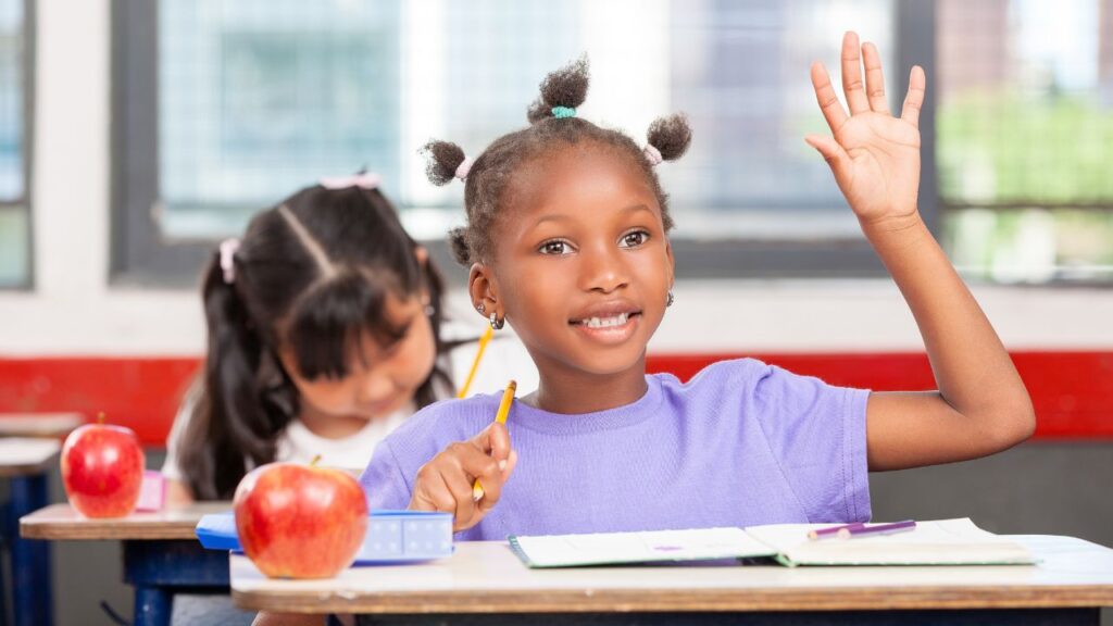 student raising her hand in a classroom
